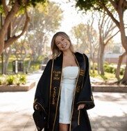 Izzie Vasiliadis in a black graduation gown and a white dress